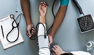 Nurse measures blood pressure – practical language training for medical staff in companies